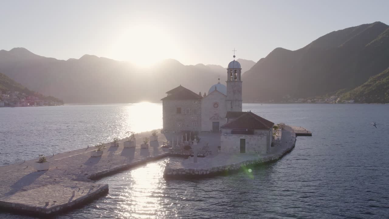 Veduta aerea della chiesa sull'isola nella Baia di Cattaro all'alba a Cattaro, Montenegro, con una splendida illuminazione all'alba, atmosfera calma, riprese drone di alta qualità che rivelano un paesaggio sereno