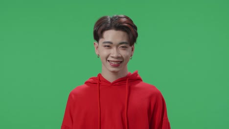 young asian transgender male warmly smiling on green screen background in the studio