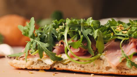 mortadella ham sandwich, traditional italian focaccia filled with thin pesto slices of mortadella, served by chef man in cafe restaurant. macro of traditional italian spanish tapas antipasti.
