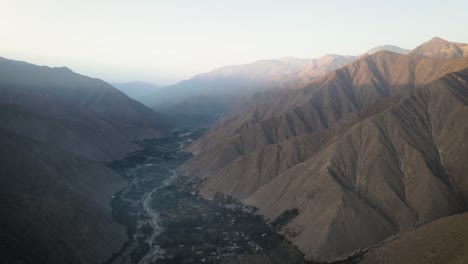 drone shot of a green valley with a river surrounded by mountains during sunset in peru