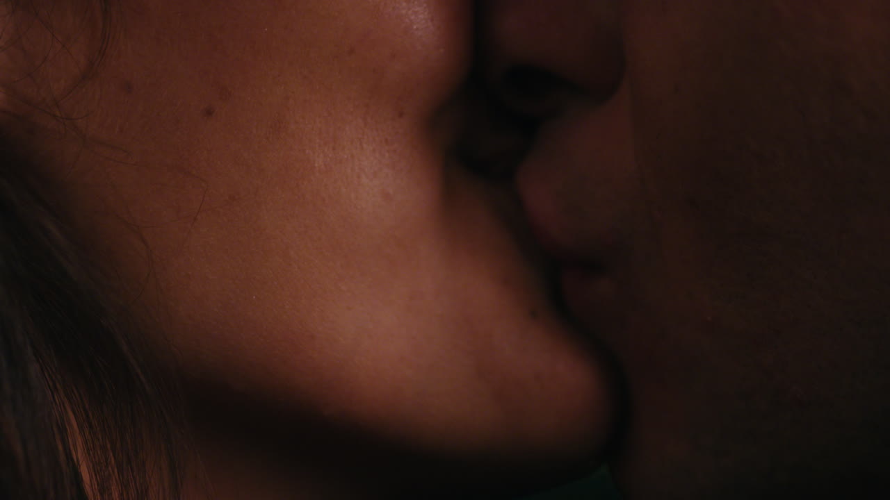 close up young caucasian couple kissing on rooftop at night enjoying romantic relationship embracing in peaceful urban evening watching beautiful city lights