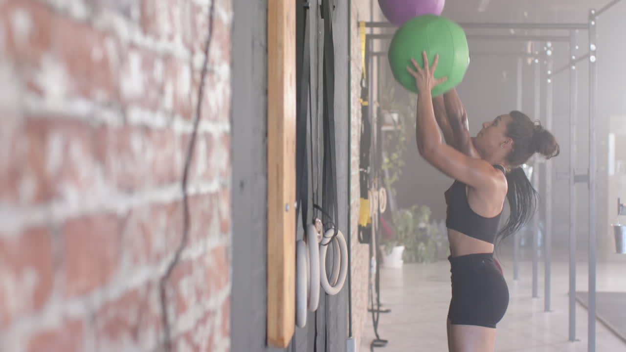 Lifting exercise balls, woman training in gym for fitness workout, copy space