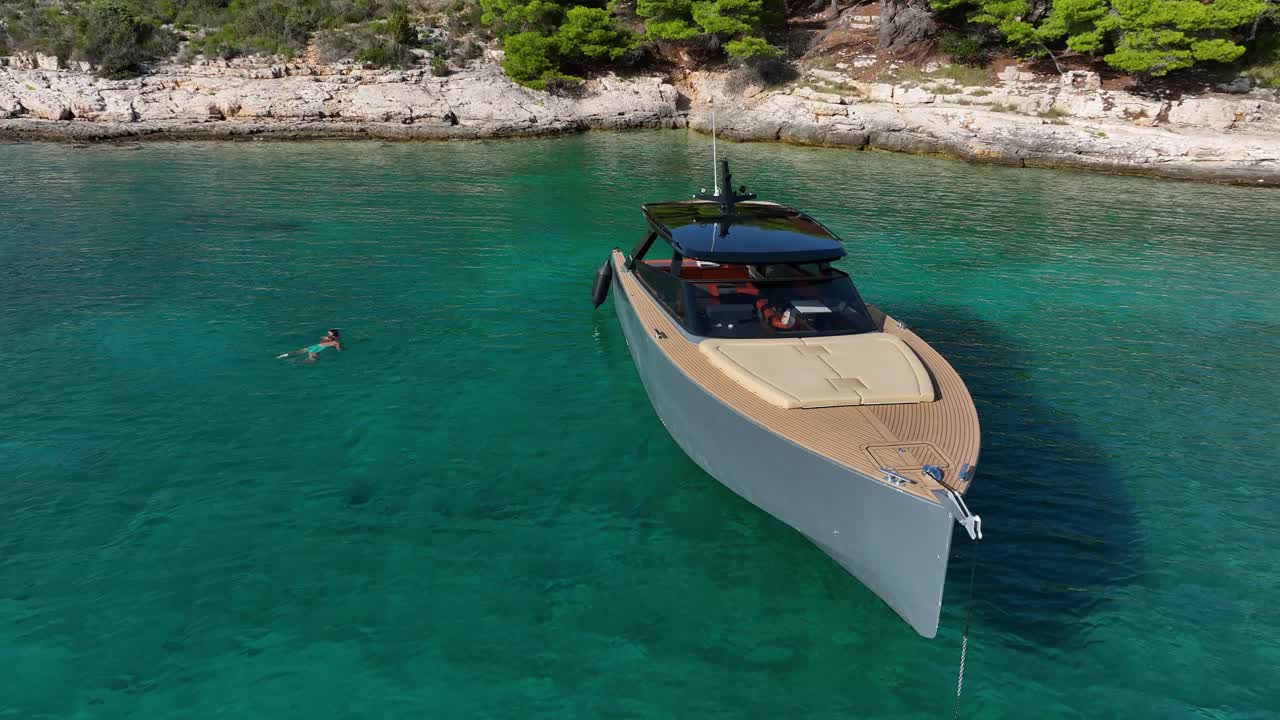 Orbit drone shot of a boat and a swimmer in Pakleni Islands in the day in Croatia