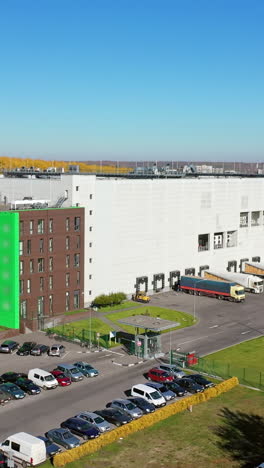 aerial view of a modern plant. huge factory and parking place with cars outdoors. contemporary industrial complex in the city. camera moves up. vertical video