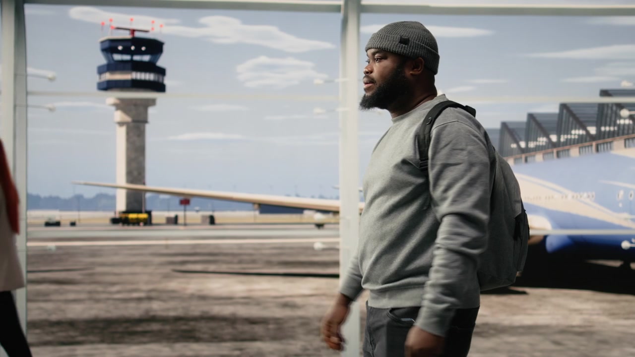 Uomo che cammina nel terminal dell'aeroporto, con uno zaino.