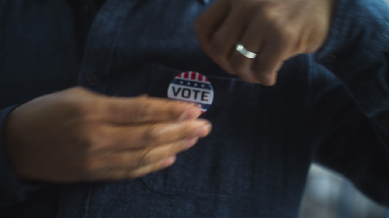 African American Man Puts on Badge with Usa Flag Logo and Inscription i Voted Anonymous African American Man Puts on Badge with Usa Flag Logo and Inscription i Voted us Citizen at Polling Station during Elections National Election Day in United States of America Close up