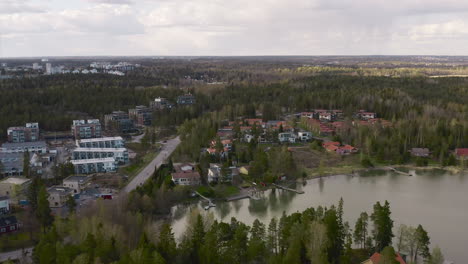 the main road leading into a town on the shore of a lake is revealed in an aerial view as it pans high above the thick forest