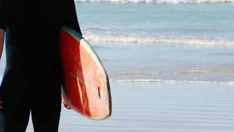 Älterer-Mann-Mit-Surfbrett-Steht-Am-Strand