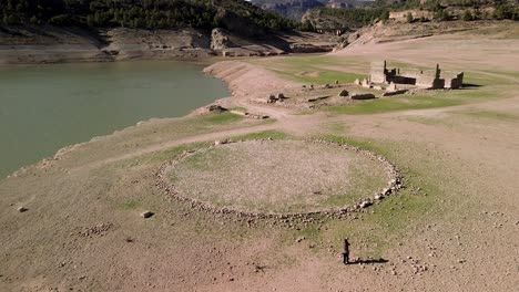 bird's-eye view of a house's ruins and a cobbled threshing floor in a rural setting beside a marsh in albacete