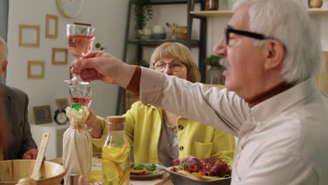 Elderly-Friends-Toasting-with-Drinks-at-Home-Dinner