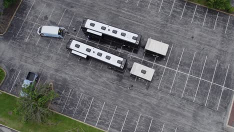 aerial view towards two tour buses parked on a parking lot - tilt, drone shot