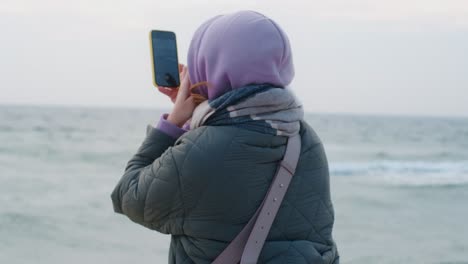 woman photographing the ocean on a cold day