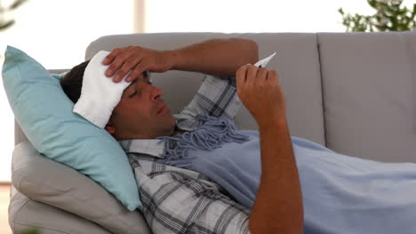 sick man lying on sofa under a blanket