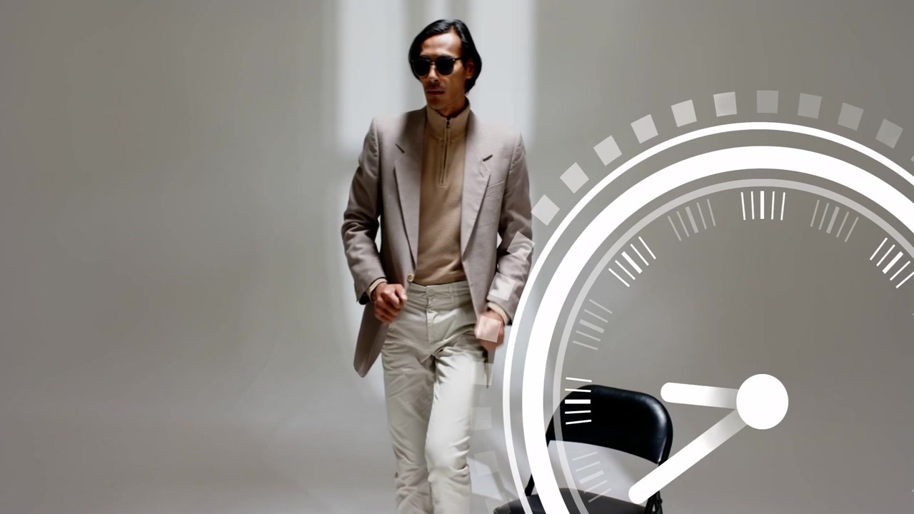 Modello uomo che sistema gli occhiali da sole, gira intorno a una sedia, si siede, posando per un overlay di orologio di moda a destra.