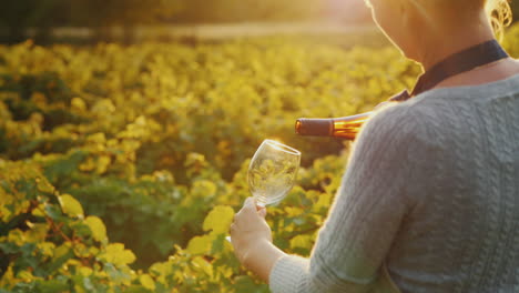 mujer vierte vino blanco en una copa de degustación privada en la bodega