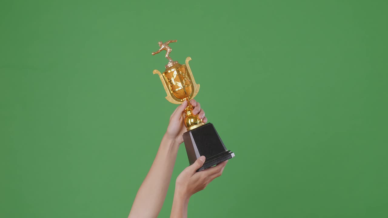 manos con un trofeo de oro