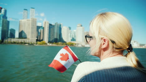 mujer sostiene la bandera canadiense por el horizonte de toronto