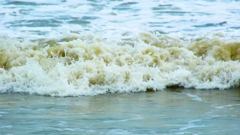 disparo en cámara lenta de olas turbias y espumosas que se estrellan en la orilla
