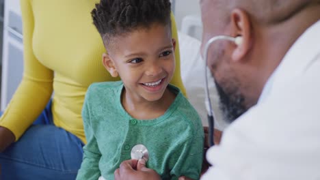 Médico-Varón-Afroamericano-Examinando-A-Un-Paciente-Infantil,-Usando-Estetoscopio-En-El-Hospital