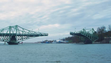 Oskara-Kalpaka-swing-bridge-closing-in-Liepaja-in-cloudy-autumn-day,-wide-shot