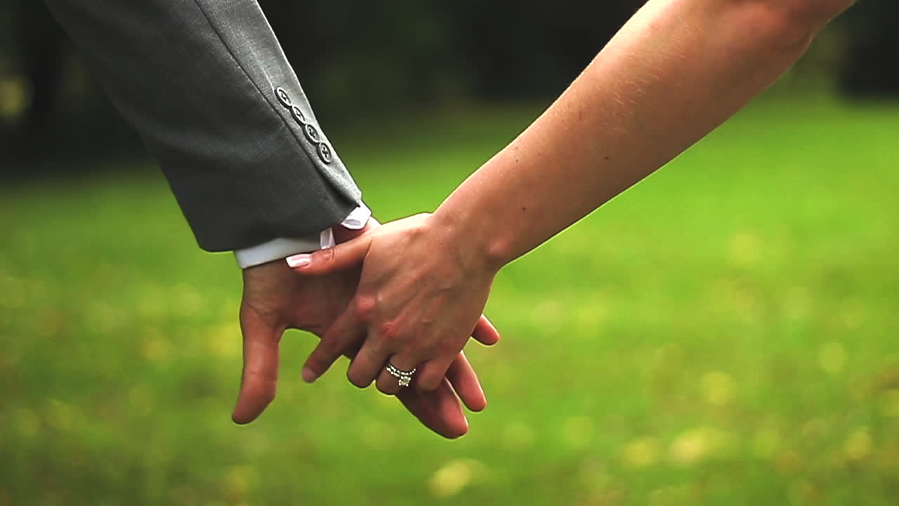 Couple holding hands walking together, tight shot, wedding