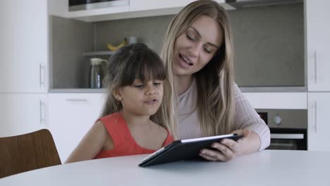 mom using tablet and for teaching little daughter