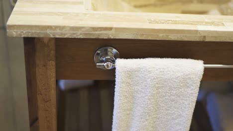 a slow-moving shot showcases bathroom furniture made of wood and nature stone, featuring a towel already hanging for guest use, emphasizing the luxurious and inviting atmosphere