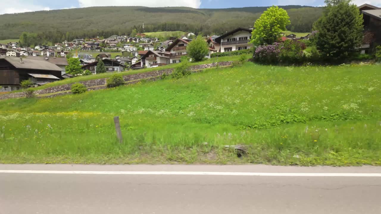 Scenic driving footage through Ortisei Sankt Ulrich, a charming alpine town in the Dolomites, with traditional houses, mountain views, and village life in northern Italy.