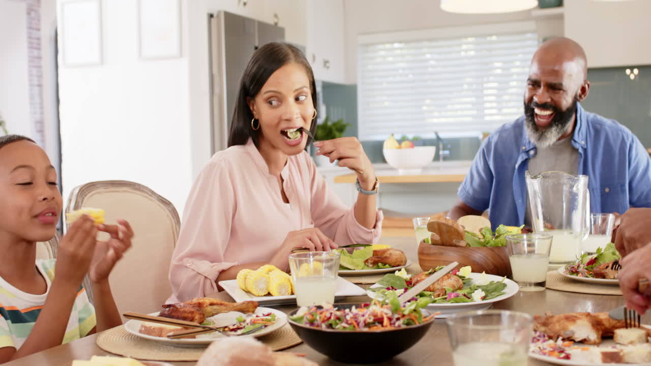Eating dinner together, african american family enjoying meal and conversation at home dining table