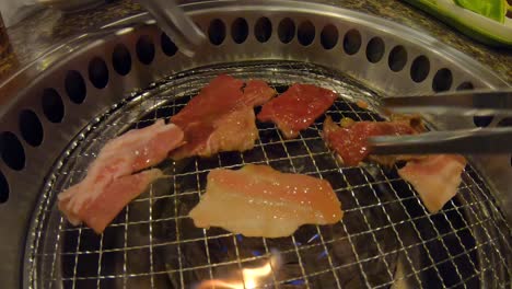 pinzas volteando carne a la parrilla en barbacoa japonesa yakiniku