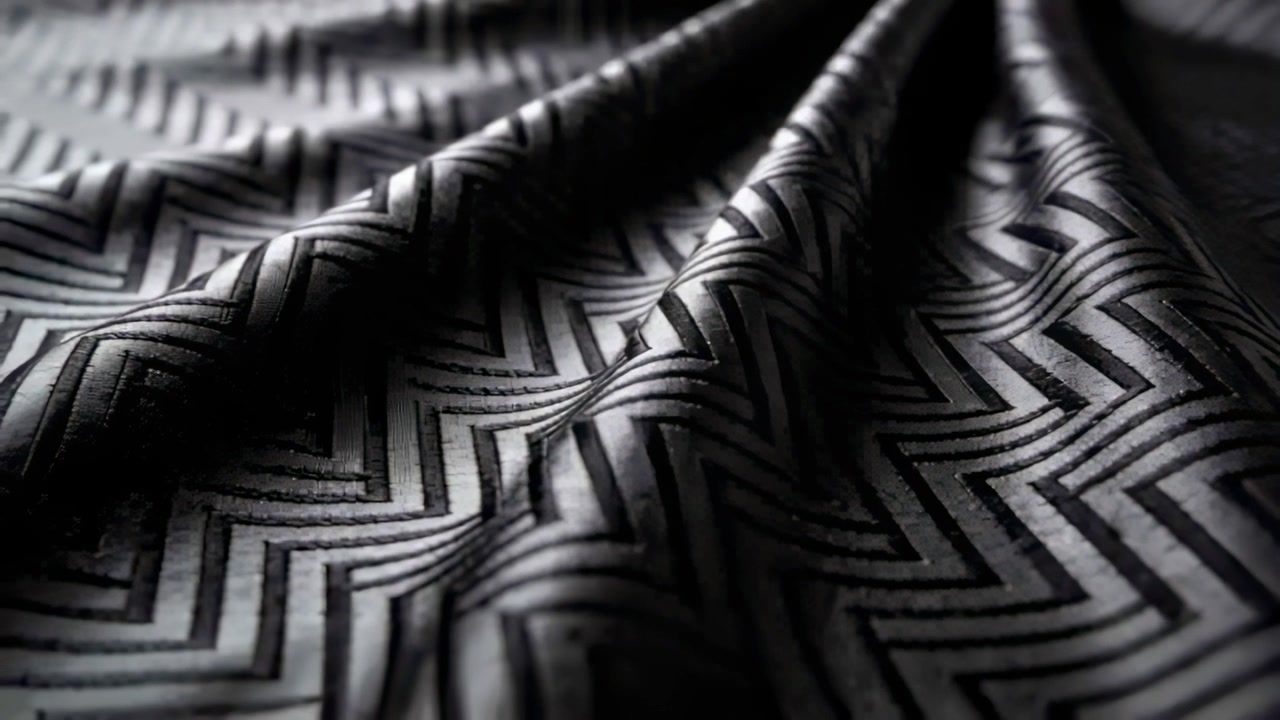 Shifting lighting revealing black textile texture on studio table to highlight zigzag pattern