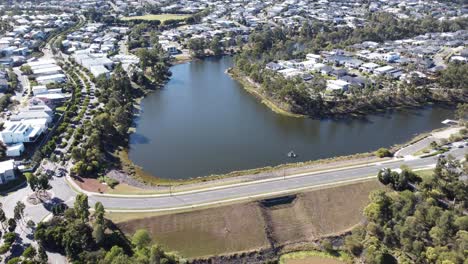 Aerial-view-of-a-manmade-lake-and-a-road-on-a-spillway-surrounded-by-private-residential-homes-in-Australia