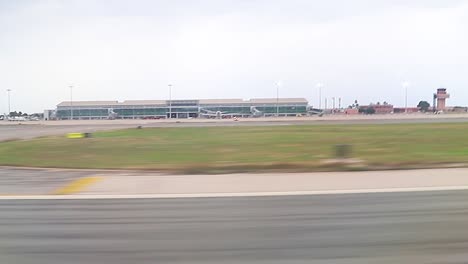 takeoff from inside plane, view through the window to the airport