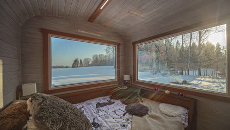 Static-view-of-cute-and-cozy-bedroom-in-a-holiday-wooden-cabin-in-the-wild-countryside-with-the-view-through-the-galss-windows-of-people-trying-to-make-a-fireplace-on-a-cold-morning-in-timelapse