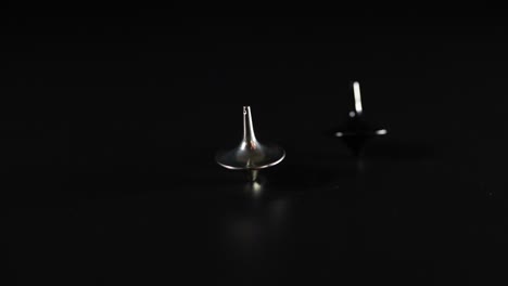 hands spinning tops on a black surface