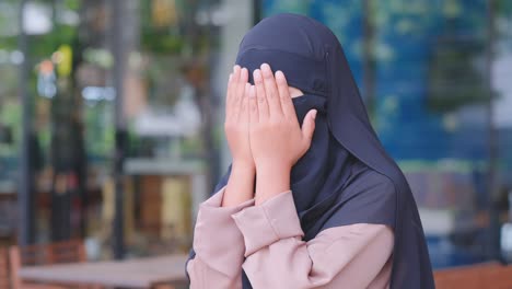 muslim girl with full face hijab pray to god activity at balcony of restaurant.   pray will success as expected when prayer express their hearts in simple words. concept of belief in their religion