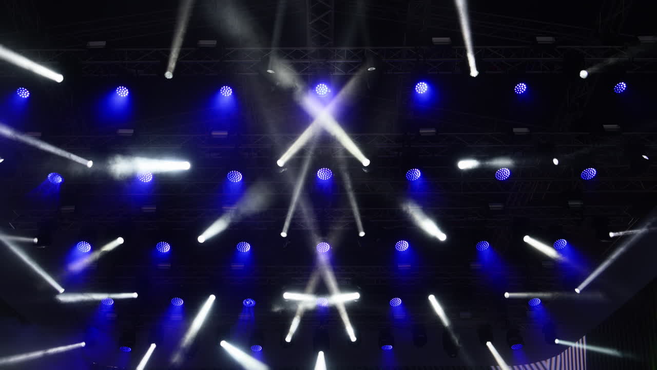 Colorful lights illuminate the stage during an exciting music event in a vibrant setting. Slow motion