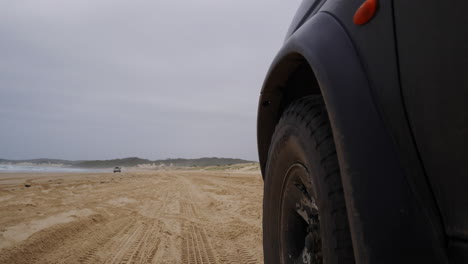 Low-perspective-shot-on-front-of-vehicle-driving-along-sandy-beach
