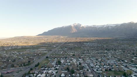 aerial view of city of ogden in utah with rugged snow-capped mountain range in background on a sunny morning