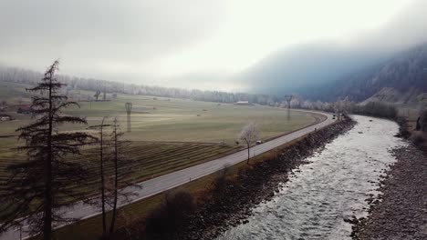 Paisaje-Aéreo-Rural-Con-Niebla,-Campos-Con-Casas-De-Campo-Y-Una-Carretera-Con-Coches,-Volando-Hasta-Ötztal,-Austria