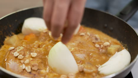 cooking southern thai massaman chicken curry with onions, carrot and peanuts