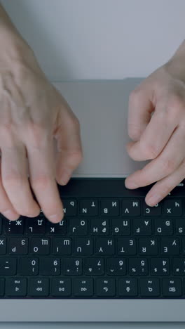 close-up of hands typing on a laptop keyboard