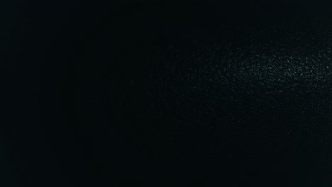 light spot moving horizontally over dark black structured background pattern