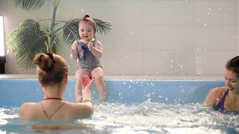 Dos-Bebés-Se-Ríen-En-La-Piscina-Y-Saltan-Al-Agua-Aplaudiendo