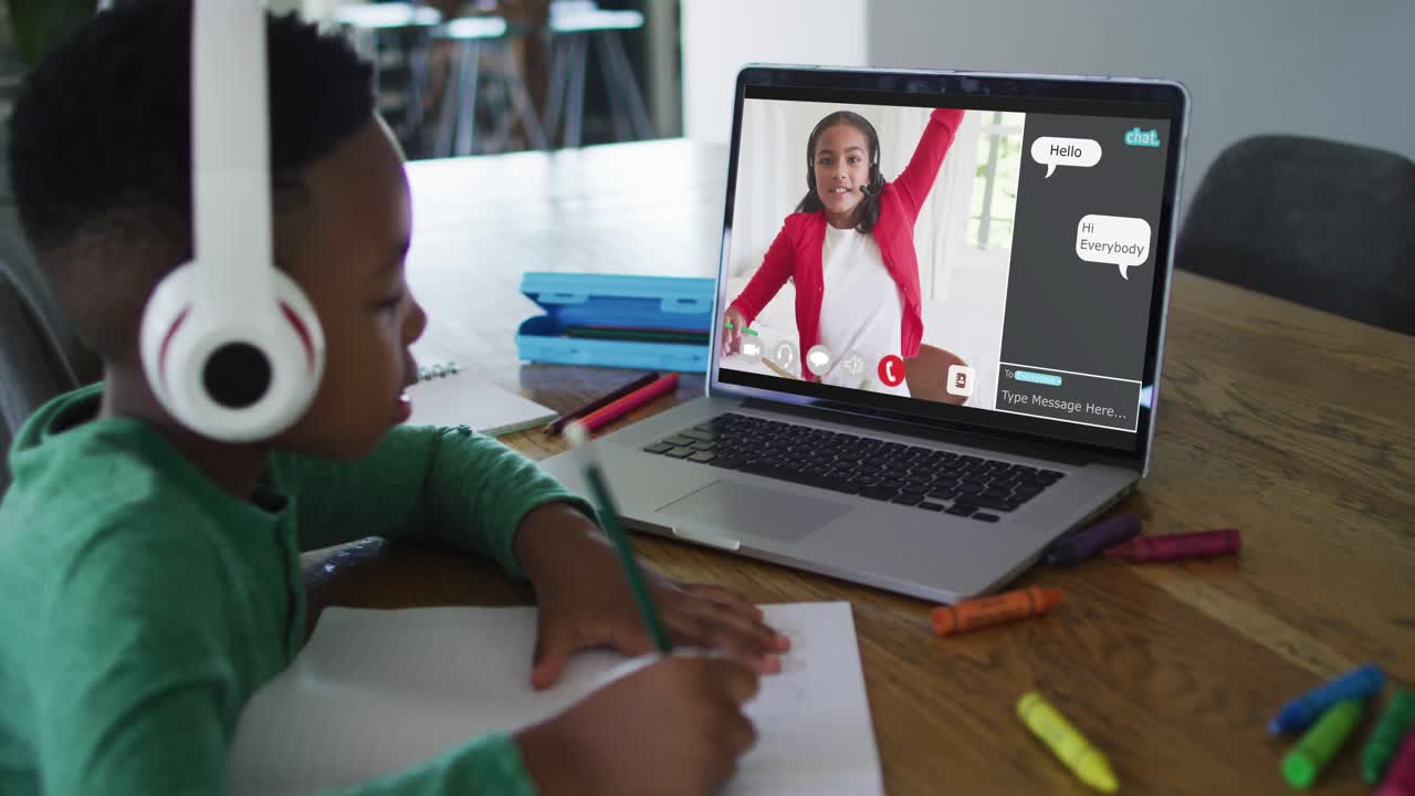 Schoolboy using laptop for online lesson at home, with school friend and web chat on screen