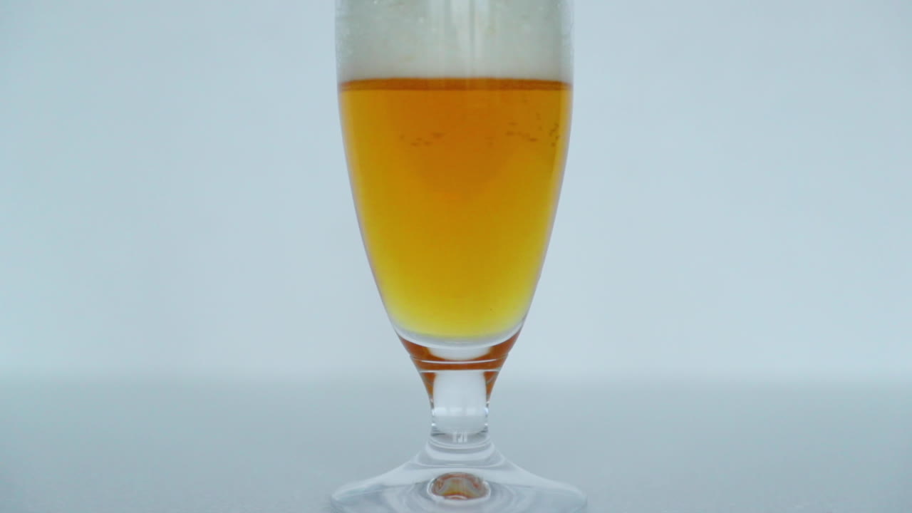 vista macro de primer plano de un vaso lleno de cerveza donde las burbujas se mueven lentamente hacia la parte superior de un vaso de hermoso color de cerveza con espuma en la parte superior en captura de cámara lenta a 120 fps