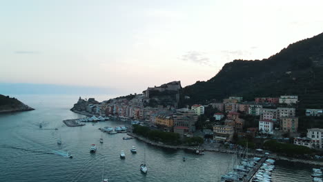 Aerial-view-of-silent-and-calm-sea-with-ships,-yachts-and-boats-parked-at-port-at-coastline-with-small-colourful-buildings-in-Portovenere-Village-in-Italy