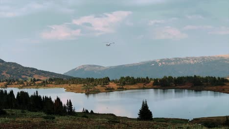 a r44 helicopter circles above a pristine mountain lake