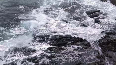 ocean waves crashing against dark rocks