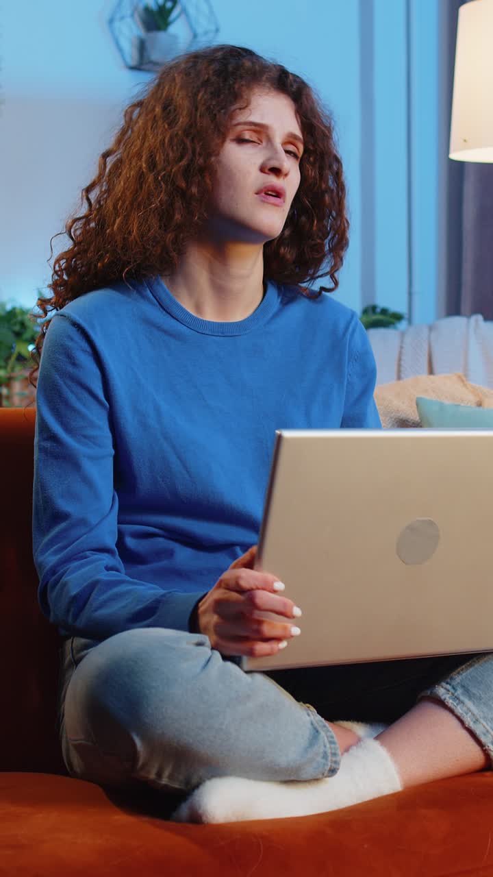 Angry displeased upset young woman using laptop netbook receiving bad news sitting on home sofa